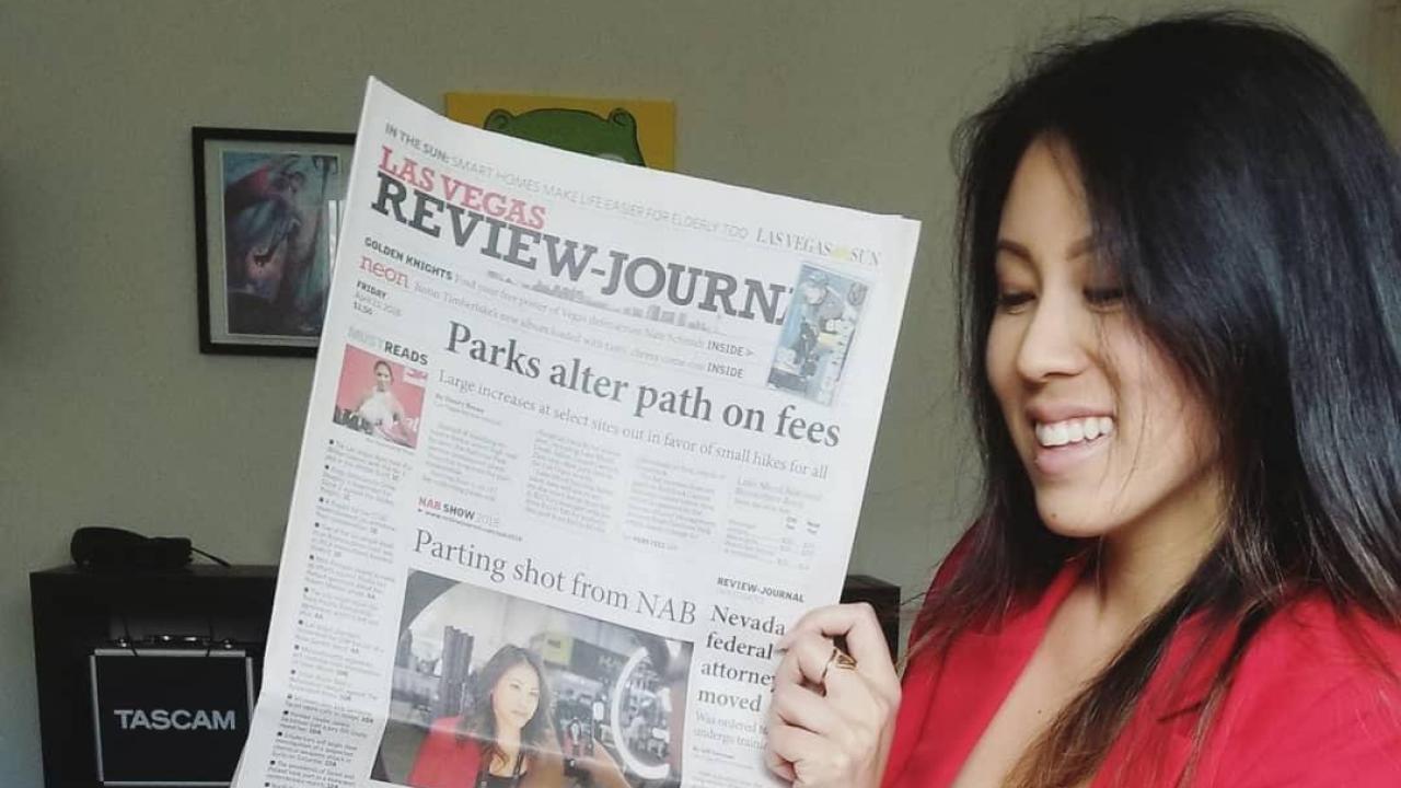 Photo: Nicki Sun looking at Las Vegas newspaper with photo of her on the front page. 