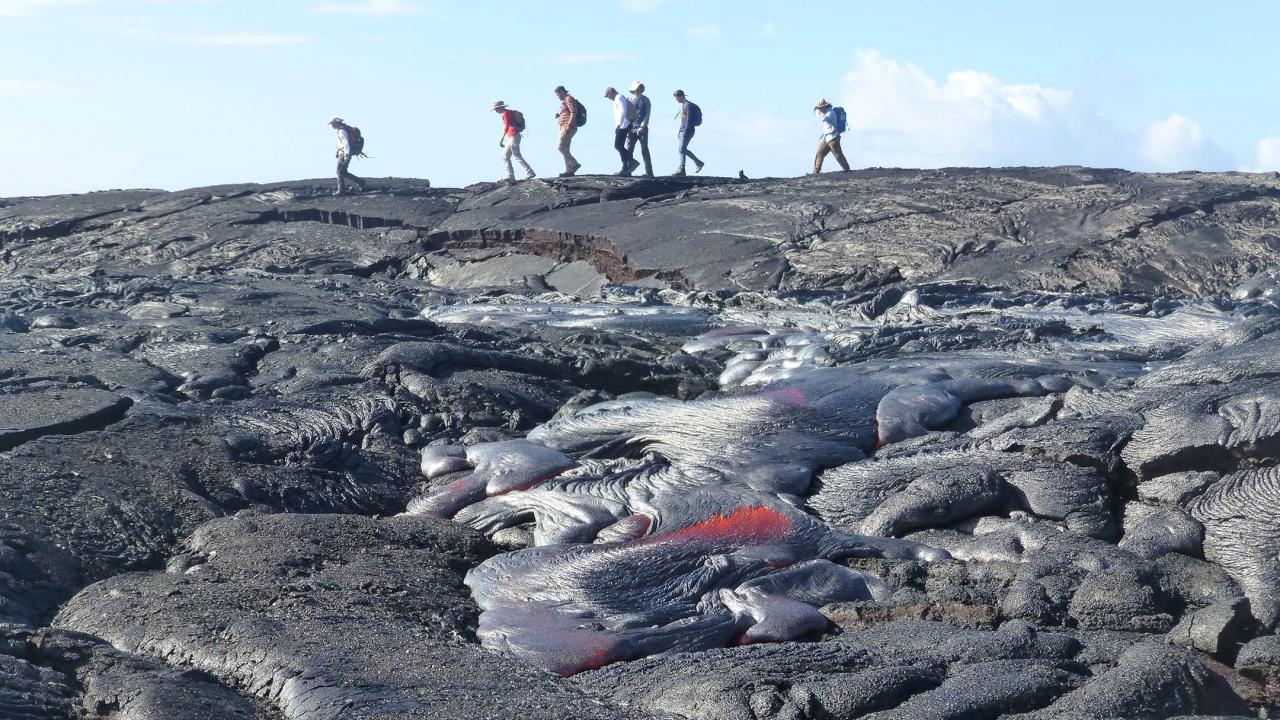 Five students from UC Davis walk across recently cooled lava in Hawaii.