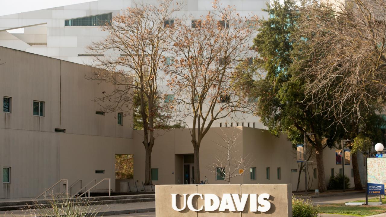 Photo of a UC Davis welcome sign and the Social Sciences and Humanities Building.