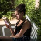 Photo: young woman sitting on a bench reading a book