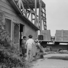 black and white photo of a man in the bed of a truck and a woman and young man standing to the left loading the truck