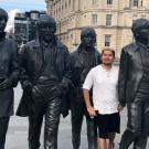Adrian Gonzales stands among four statues commemorating the members of The Beatles on a London street